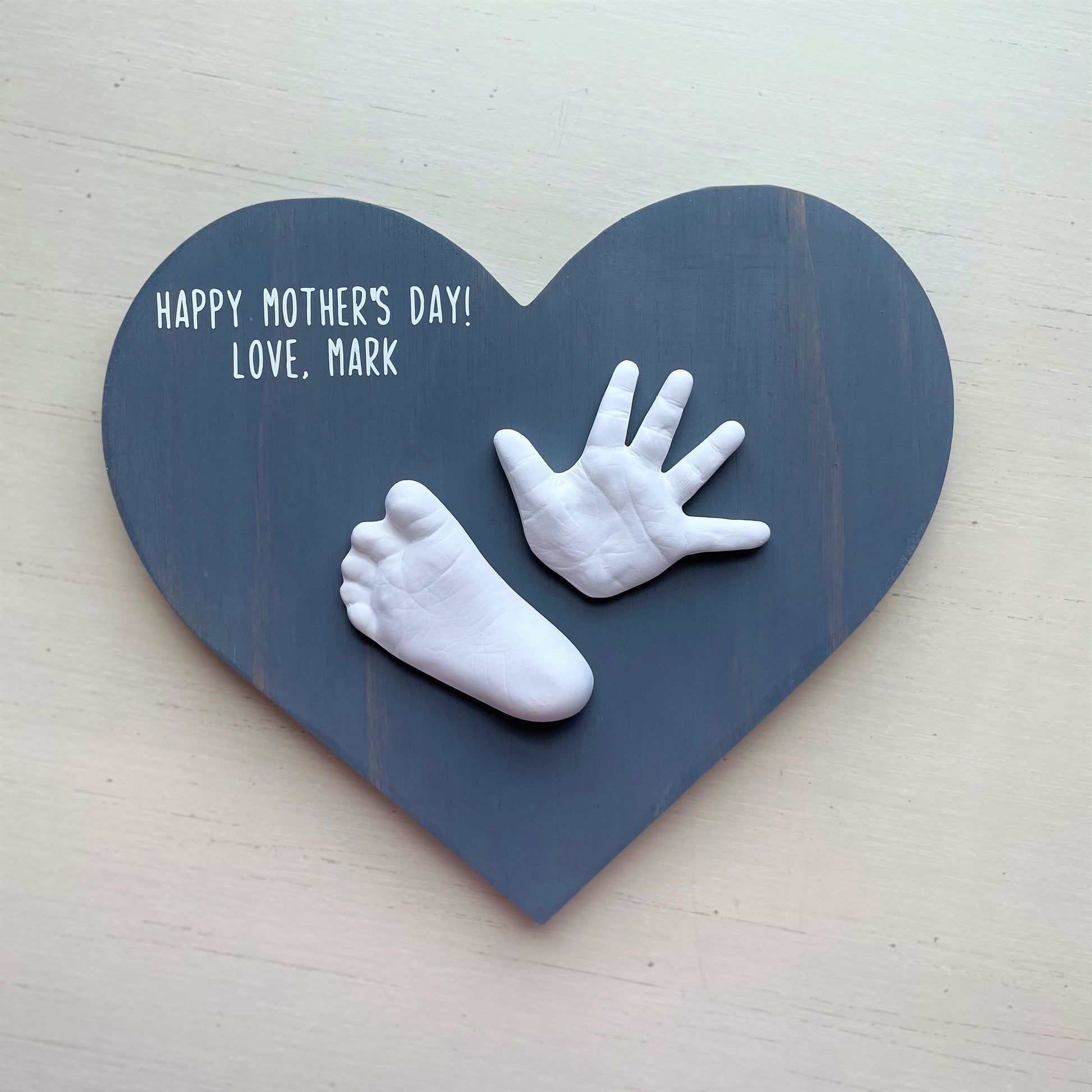 Gray wooden heart plaque with baby's hand and foot casts